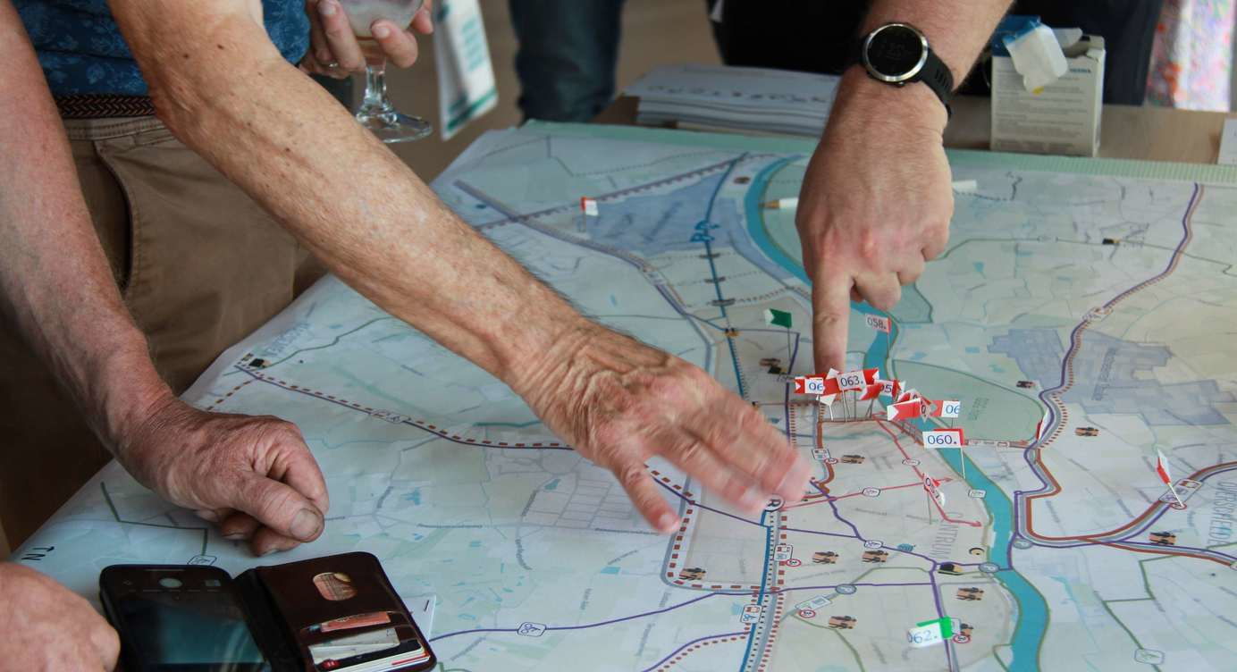 Deelnemers aan een dialoogmarkt geven info op een plan